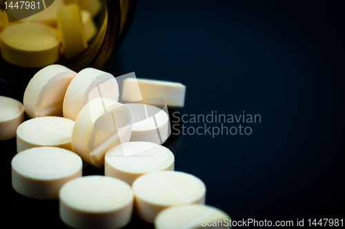 Image of Medical pills out of their bottle on black background