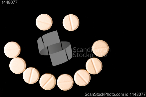 Image of Smiling face made out of pills on black background