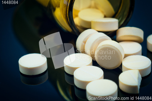 Image of Medical pills out of their bottle on black background