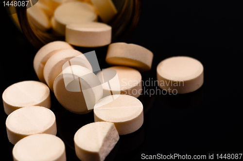 Image of Medical pills out of their bottle on black background