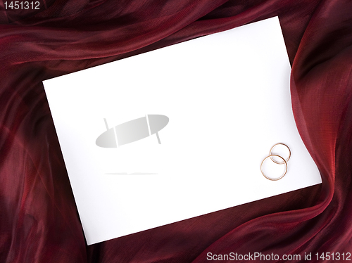 Image of white frame in silk and two wedding rings 