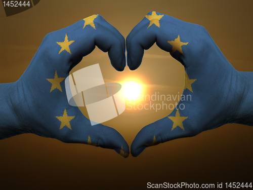 Image of Heart and love gesture by hands colored in eu flag during beauti