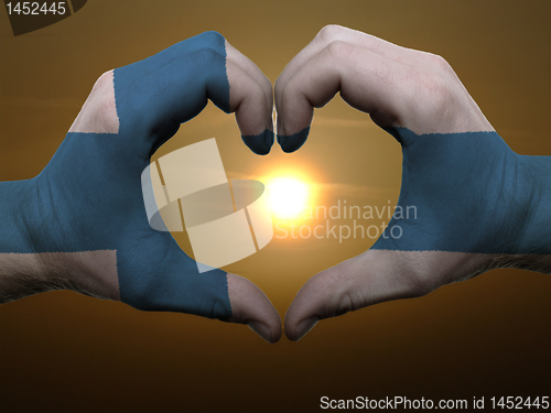 Image of Heart and love gesture by hands colored in finland flag during b
