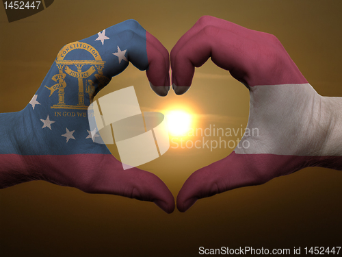 Image of Heart and love gesture by hands colored in georgia flag during b