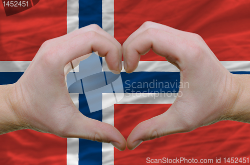 Image of Heart and love gesture showed by hands over flag of norway backg