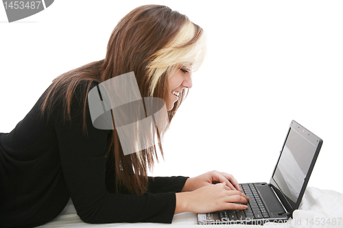 Image of Beautiful girl relaxing on the bed with her laptop 