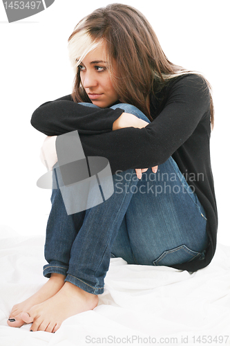 Image of Sad girl teenager sits twining arms about legs. Isolated on a wh