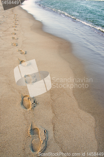 Image of Foot imprints beside waves reaching margin. Romantic stroll.