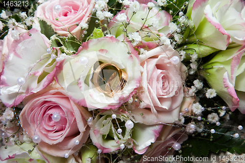 Image of wedding rings on bouquet of bride 