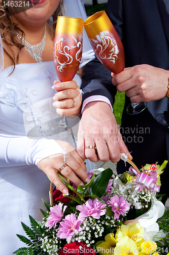 Image of hands of brid and groom with bouquet and glasses of champagne