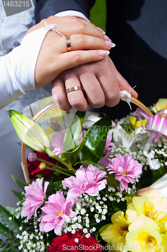 Image of hands of bride and groon on wedding bouquet 