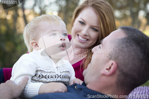 Image of Cute Child Looks Up to Sky as Young Parents Smile