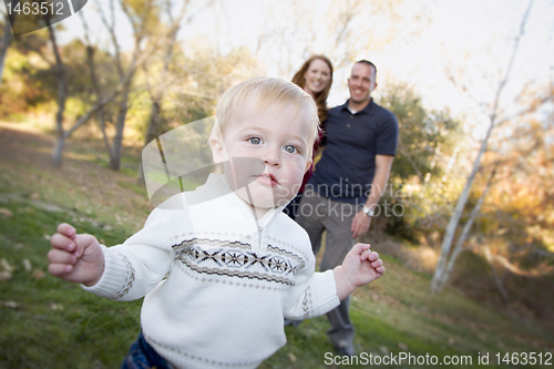 Image of Cute Young Boy Walking as Parents Look On From Behind