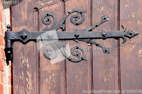 Image of Detail of decorative hinges holding wooden door.