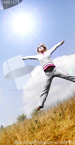 Image of Happy woman jumping against blue sky