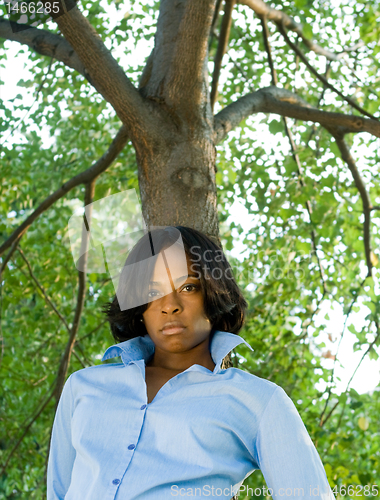 Image of Pouting African American Woman Leaning Tree