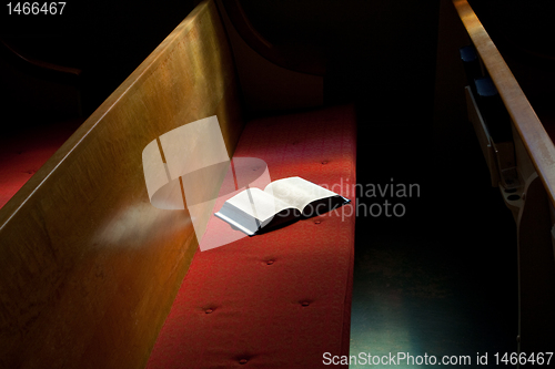 Image of Open Bible Lying on Church Pew in Narrow Sunlight Band