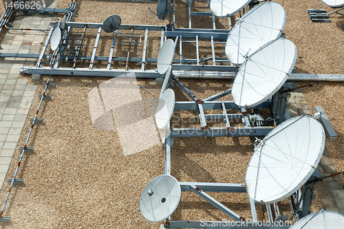 Image of Collection of Large Satellite Dishes on Flat Gravel Roof