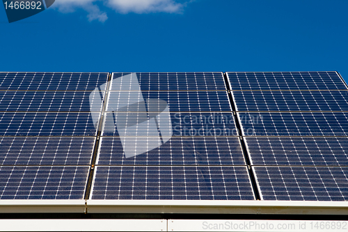 Image of Row of Photovoltaic Solar Panels on Roof Against Blue Sky      