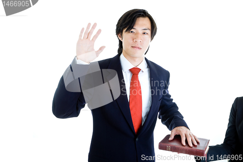 Image of Asian Man Raised Hand Swearing on Bible Isolated White Backgroun