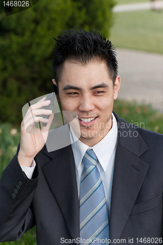 Image of Asian Businessman Holding Cell Phone Outside Park