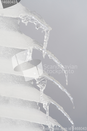 Image of Row of Icicles Hanging off a Roof Gray Sky Background