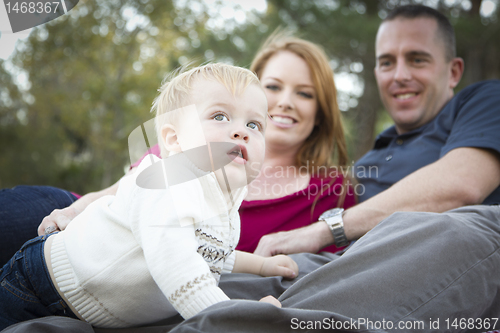 Image of Cute Child Looks Up to Sky as Young Parents Smile