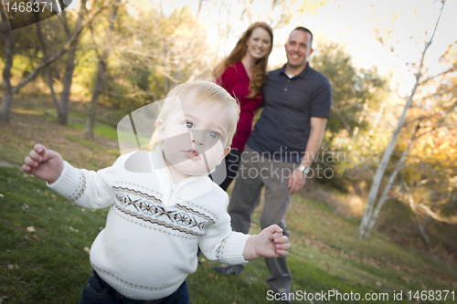 Image of Cute Young Boy Walking as Parents Look On From Behind