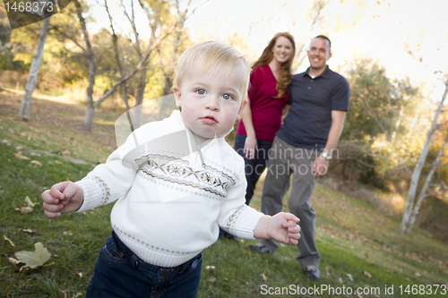 Image of Cute Young Boy Walking as Parents Look On From Behind