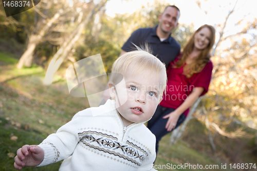 Image of Cute Young Boy Walking as Parents Look On From Behind