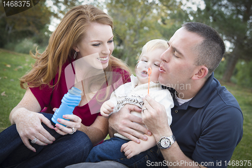 Image of Young Parents Blowing Bubbles with their Child Boy in Park