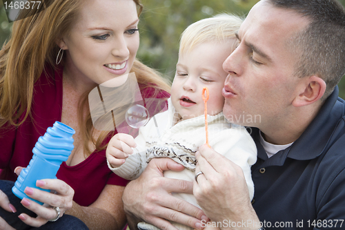 Image of Young Parents Blowing Bubbles with their Child Boy in Park