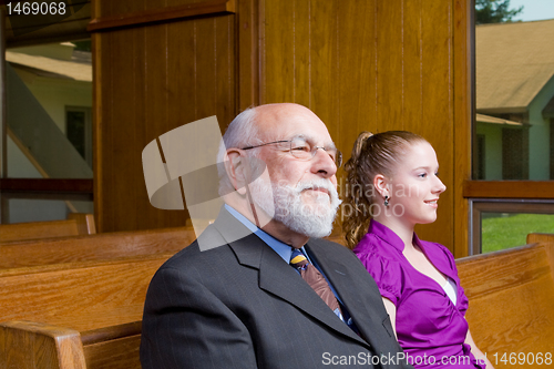 Image of Senior Caucasian Man and Young Woman Sitting in Church Pew 