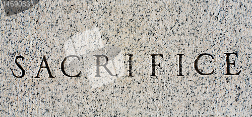 Image of Word "Sacrifice" Carved in Gray Granite Stone
