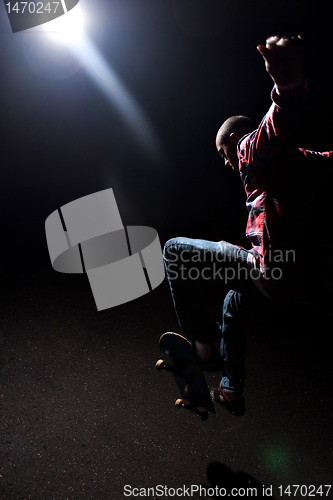 Image of Skateboarder Jumping Under Dramatic Lighting