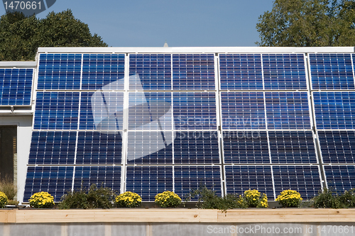 Image of Row of Solar Panels on Roof Against Blue Sky