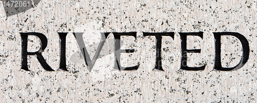 Image of Word "Riveted" Carved in Gray Granite Stone