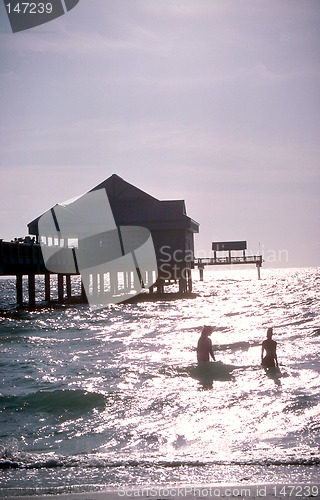 Image of People wading in the water near pier