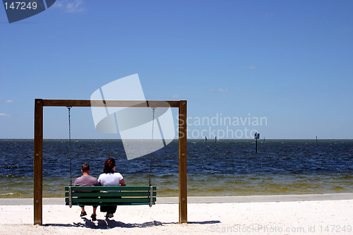 Image of Couple sitting on a swing at the beach