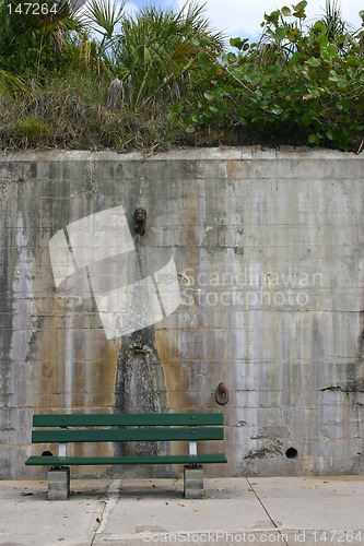 Image of Green bench set against a tall concrete wall