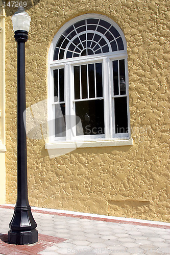 Image of A black lamppost and window against yellow stucco wall