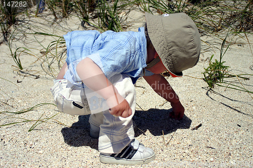 Image of Boy on beach picking up pebbles