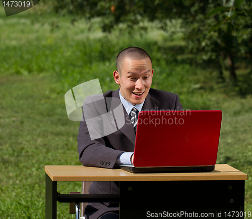 Image of man with red laptop working outdoors