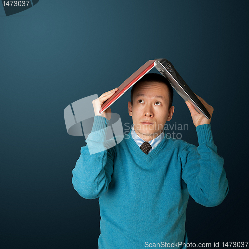 Image of young businessman hides under the laptop