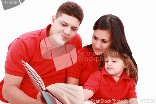 Image of Family sitting on floor reading book at home