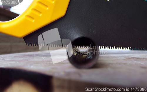 Image of Wooden saw used for cutting a metal pipe