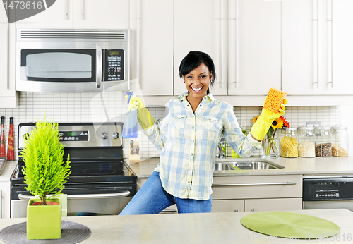 Image of Young woman cleaning kitchen