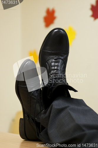 Image of Black leather shoes crossed on table