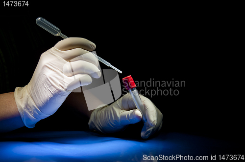 Image of Hands in white gloves hold pipette