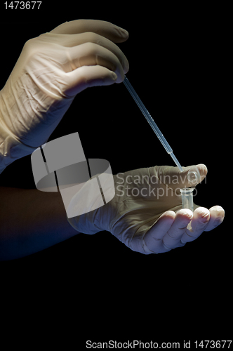 Image of Hands in white gloves hold pipette